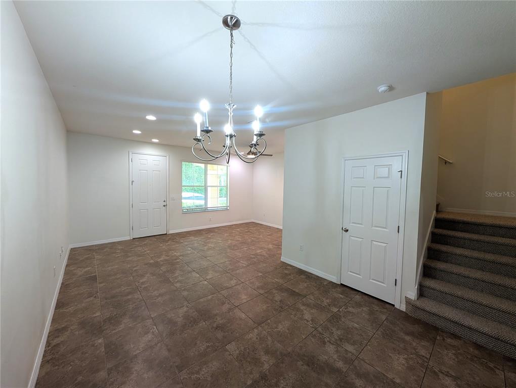 A room with tile flooring, a chandelier, a white door, and stairs with carpet — 14161 STOWBRIDGE AVENUE, TAMPA, FL