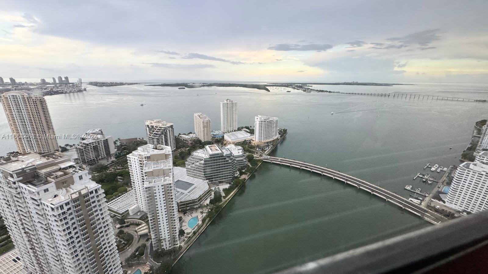 An aerial view shows high-rise apartment buildings, a bridge, and a bay under a cloudy sky — 495 Brickell Ave # 4902, Miami FL 33131, MIAMI, FL