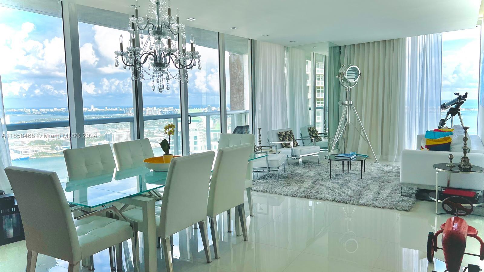 A bright dining and living area features floor-to-ceiling windows with expansive ocean and city views — 495 Brickell Ave # 4902, Miami FL 33131, MIAMI, FL