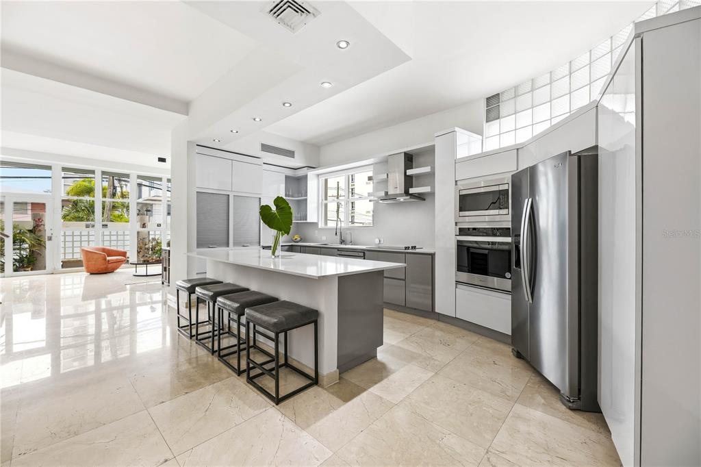 A modern kitchen features a white island with bar stools, stainless appliances, and tile flooring — 1362 MAGDALENA AVENUE UNIT Villa 109, SAN JUAN, PR