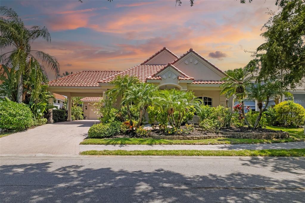 A single-story house with a tile roof, a carport, and lush landscaping in the front yard — 4770 MAINSAIL DRIVE, BRADENTON, FL
