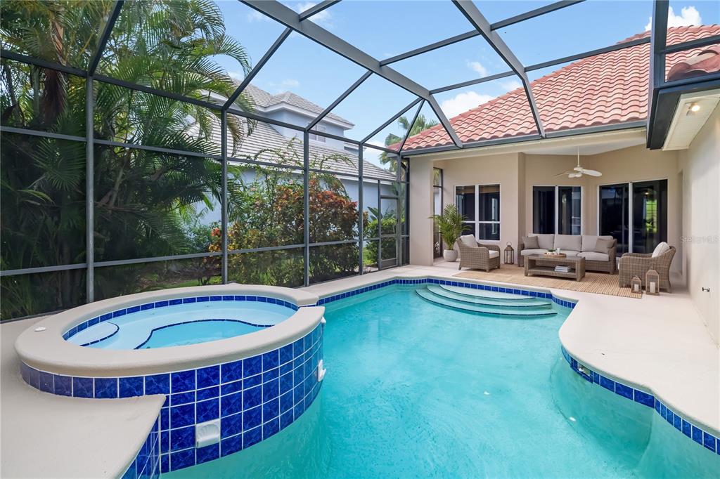 A screened-in patio features a swimming pool, a raised tiled spa, and outdoor furniture — 4770 MAINSAIL DRIVE, BRADENTON, FL