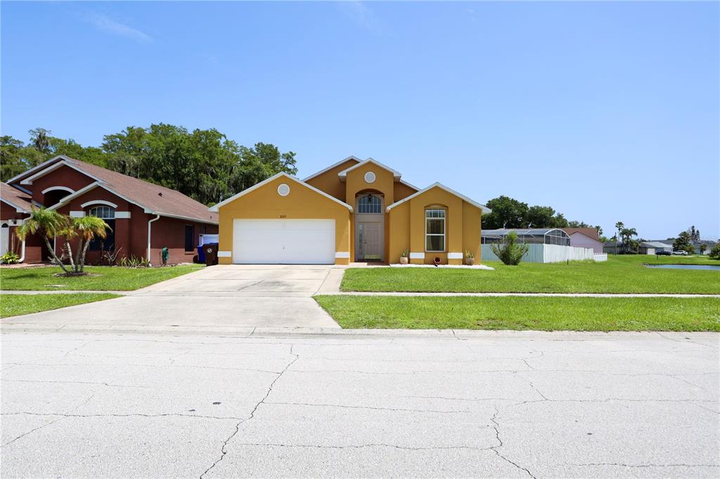A yellow single-story house with a white garage door and a concrete driveway — 2169 REMINGTON POINTE BOULEVARD, KISSIMMEE, FL