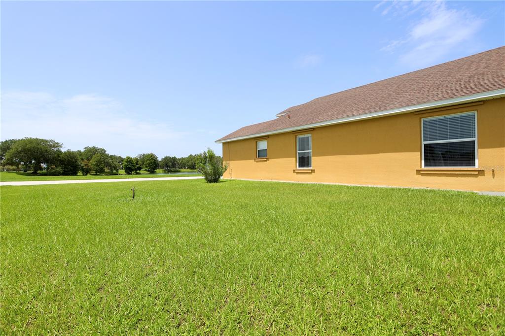 The exterior side of a yellow house with a brown roof and a grassy yard — 2169 REMINGTON POINTE BOULEVARD, KISSIMMEE, FL