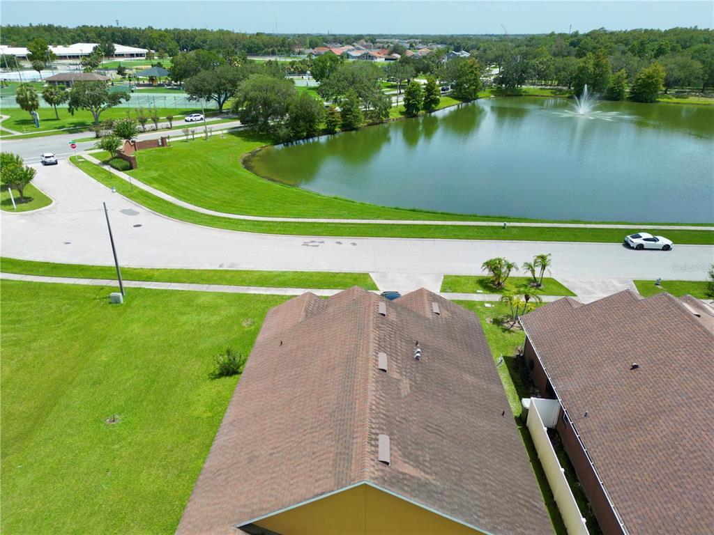 An aerial view shows a residential roof, a curved pond with a fountain, and landscaping — 2169 REMINGTON POINTE BOULEVARD, KISSIMMEE, FL