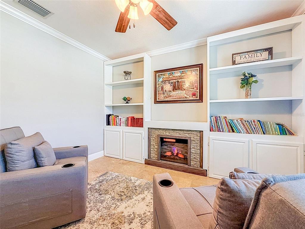 A living room features a stone fireplace, built-in shelving, and two gray armchairs — 420 HARTFORD HEIGHTS STREET, SPRING HILL, FL