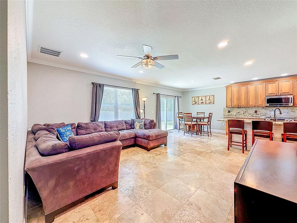 An open-concept living room and kitchen featuring tile flooring, a sectional sofa, and cabinetry — 420 HARTFORD HEIGHTS STREET, SPRING HILL, FL