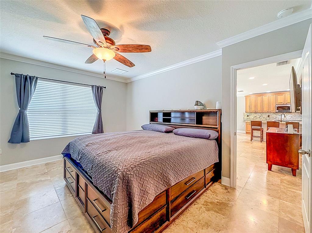 A bedroom with a wooden storage bed, tile flooring, and a view into a kitchen — 420 HARTFORD HEIGHTS STREET, SPRING HILL, FL