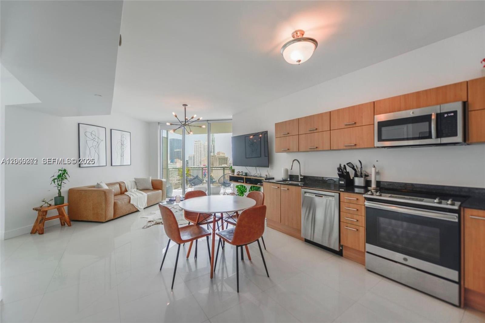 An open-concept living area features a kitchen with wood cabinets, a dining set, and balcony — 350 S Miami Ave # 1911, Miami FL 33130, MIAMI, FL