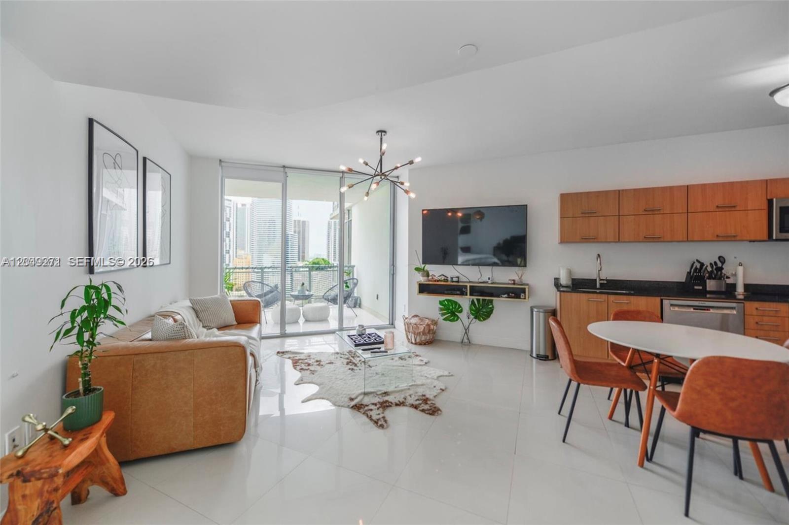 A modern living room and kitchen area features a leather sofa, dining set, and balcony — 350 S Miami Ave # 1911, Miami FL 33130, MIAMI, FL