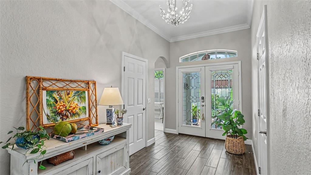 An entryway features a white console table, a chandelier, and double glass-paned front doors — 2775 HIGHLANDS CREEK DRIVE, LAKELAND, FL