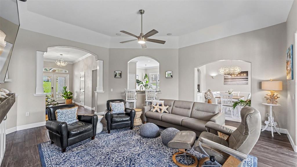 A living room features a grey sofa, leather armchairs, a patterned rug, and arched doorways — 2775 HIGHLANDS CREEK DRIVE, LAKELAND, FL