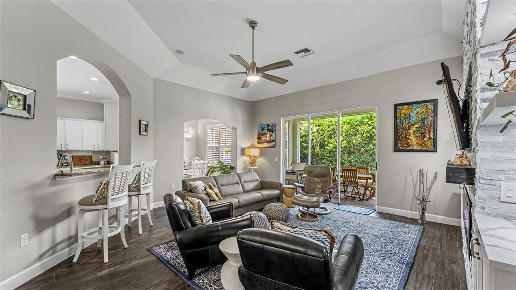 A living room features a vaulted ceiling, a stone fireplace, and sliding glass doors — 2775 HIGHLANDS CREEK DRIVE, LAKELAND, FL