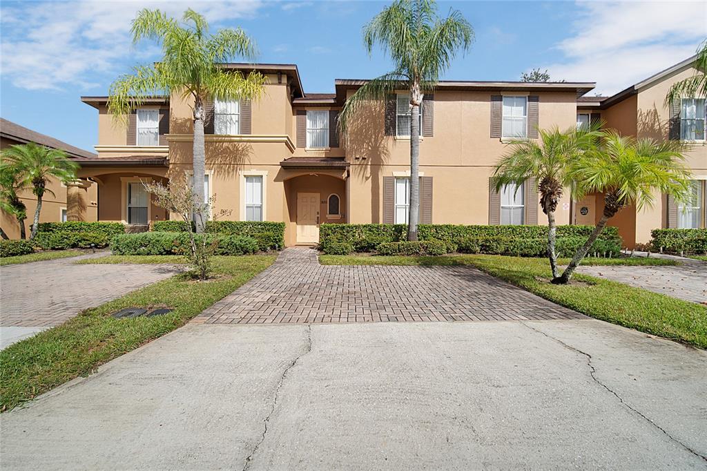 A two-story tan stucco townhouse with a paved driveway and palm trees in front — 2632 CALABRIA AVENUE, DAVENPORT, FL