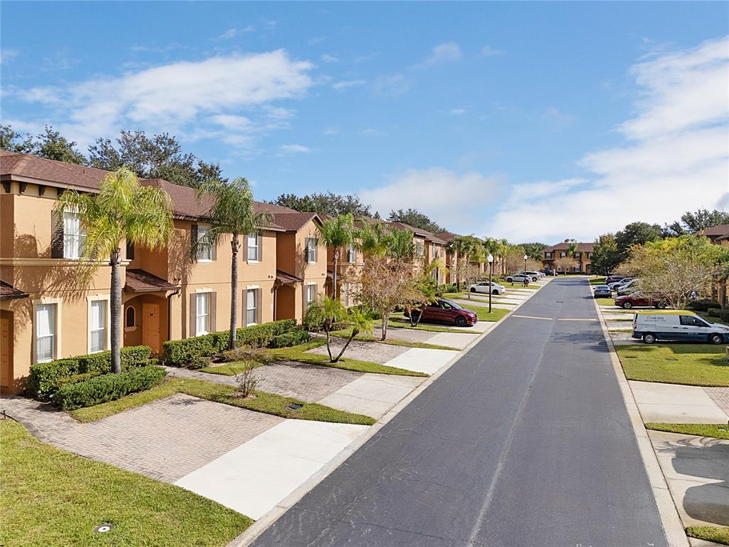 An exterior view of a row of tan townhomes with palm trees and parked cars — 2632 CALABRIA AVENUE, DAVENPORT, FL