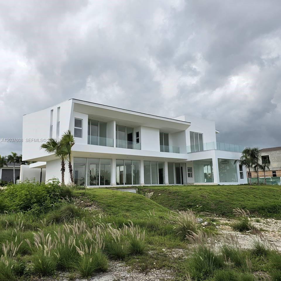 A modern two-story white house with large glass windows and a grassy yard — 0 Cap Cana., FL