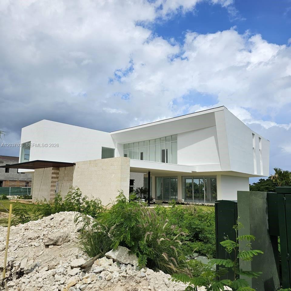 A modern white two-story house features large glass windows and a stone accent wall — 0 Cap Cana., FL
