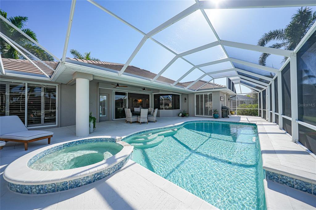 A screened-in patio features a swimming pool, a raised hot tub, and outdoor dining furniture — 523 SAINT GIRONS COURT, PUNTA GORDA, FL