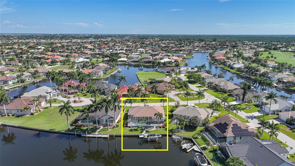 An aerial view shows a waterfront house with a pool cage and a private dock — 523 SAINT GIRONS COURT, PUNTA GORDA, FL