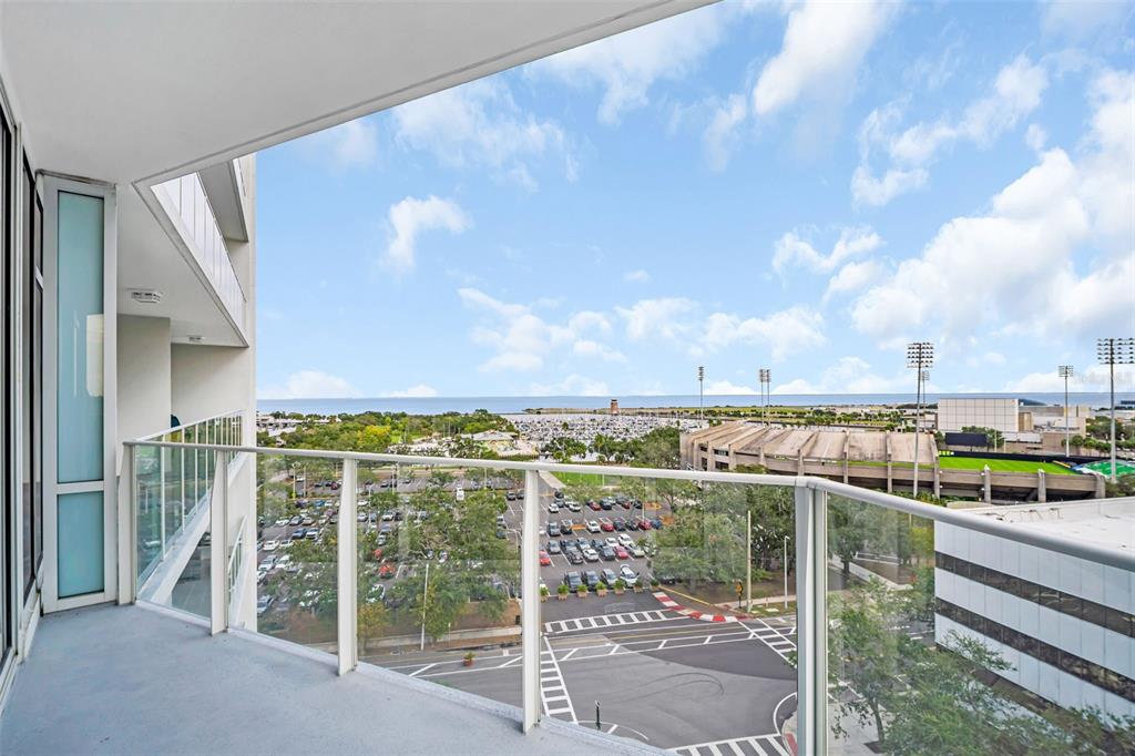 A high-rise balcony overlooks a parking lot, a marina, and a stadium near the ocean — 175 1ST STREET S UNIT 905, ST PETERSBURG, FL
