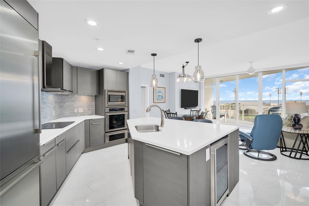 A modern kitchen features gray cabinetry, white countertops, a central island, and floor-to-ceiling windows — 175 1ST STREET S UNIT 905, ST PETERSBURG, FL