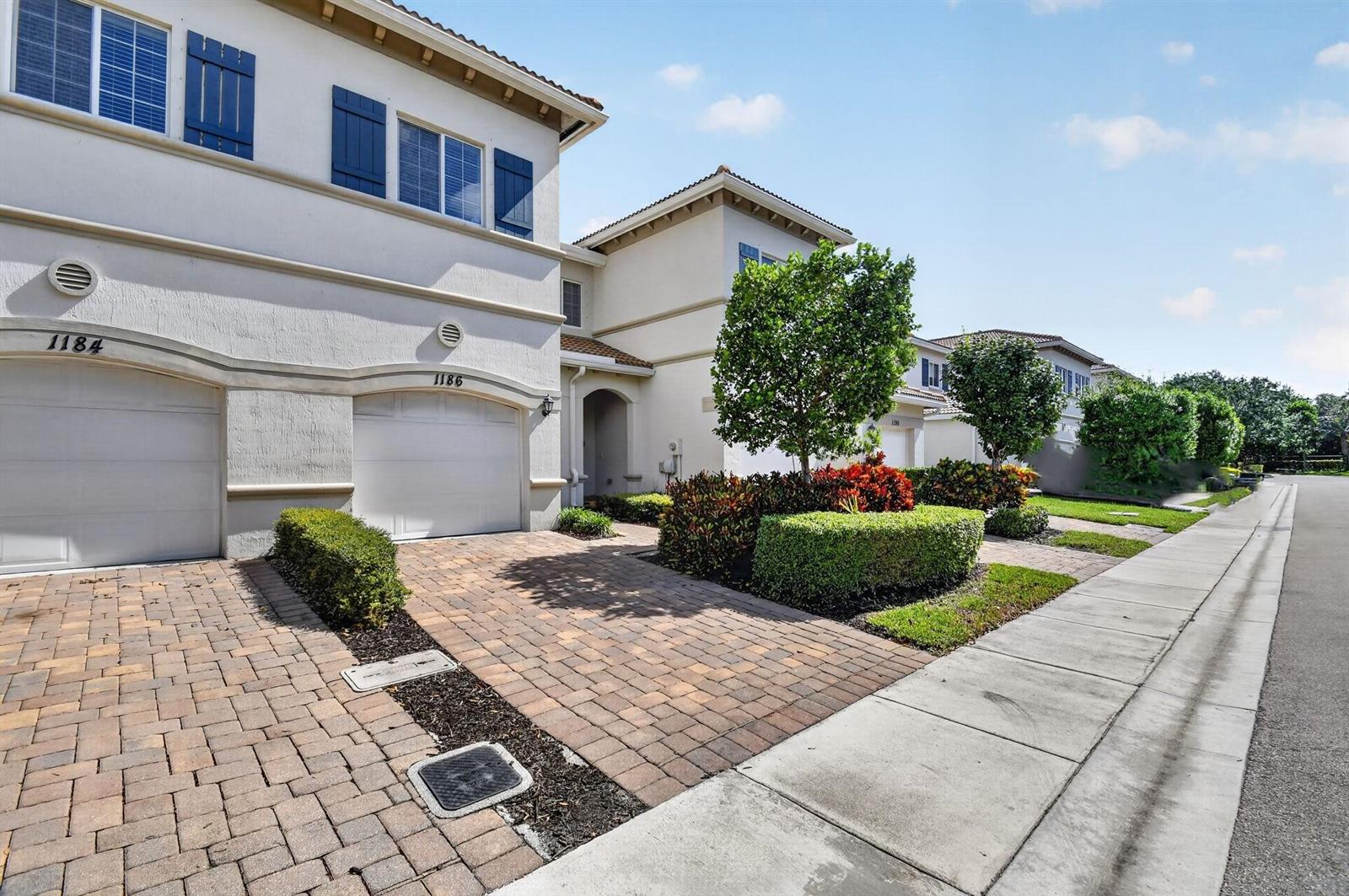 A street-level view of two attached townhomes with paved driveways and manicured landscaping — 1186 Paisley Court, FL 33461, FL