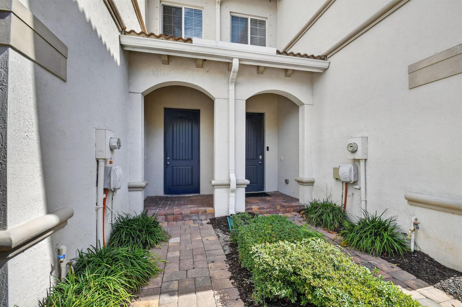 Two dark blue front doors are set within arched alcoves of a stucco building exterior — 1186 Paisley Court, FL 33461, FL