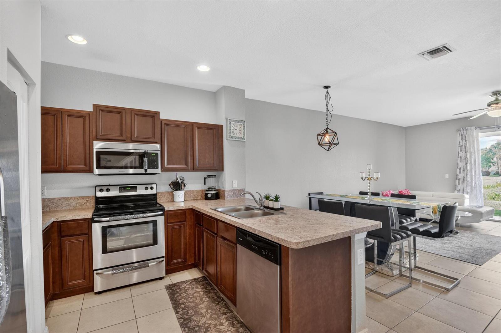 A kitchen with dark wood cabinets, stainless steel appliances, and a peninsula island — 1186 Paisley Court, FL 33461, FL