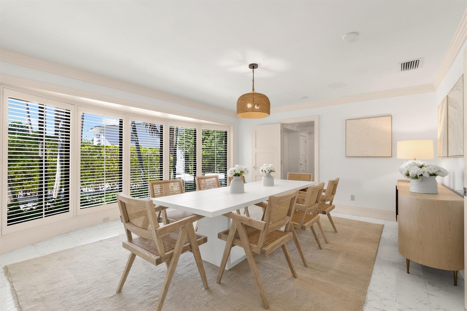 A bright dining room features a white table, cane chairs, and large plantation-shuttered windows — 1435 N Ocean Way, Palm Beach FL 33480, PALM BEACH, FL