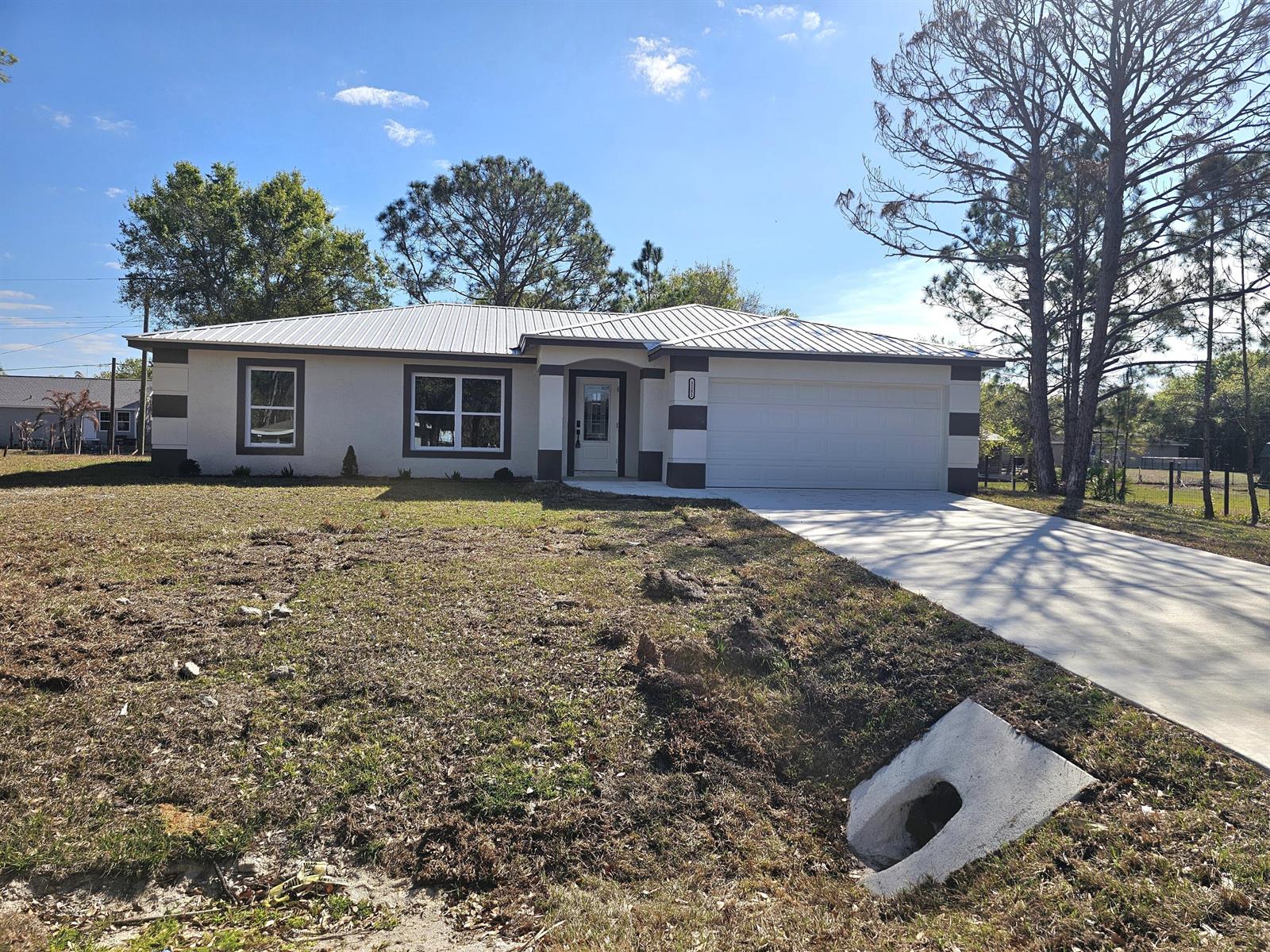 A single-story house with a white metal roof, light-colored stucco, and a concrete driveway — 2964 NW 36th Avenue, Okeechobee FL 34972, OKEECHOBEE, FL