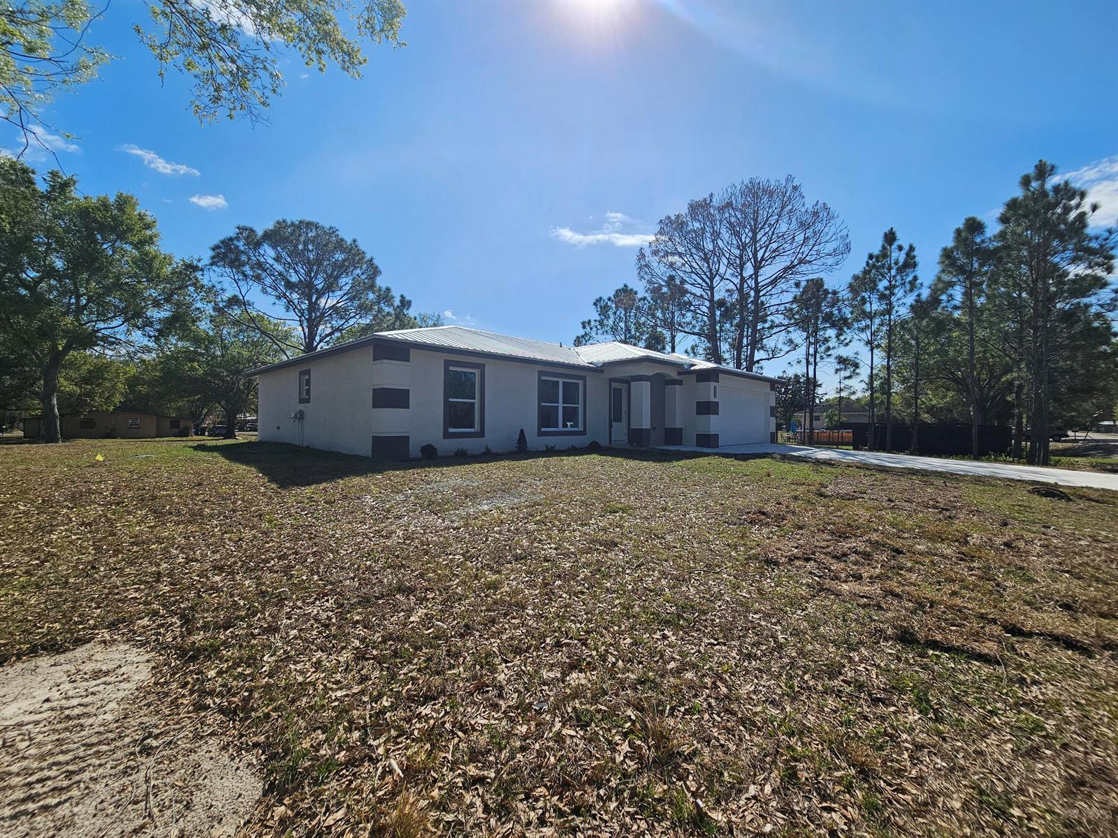 A single-story house with a light-colored exterior and a metal roof sits on a lot — 2964 NW 36th Avenue, Okeechobee FL 34972, OKEECHOBEE, FL