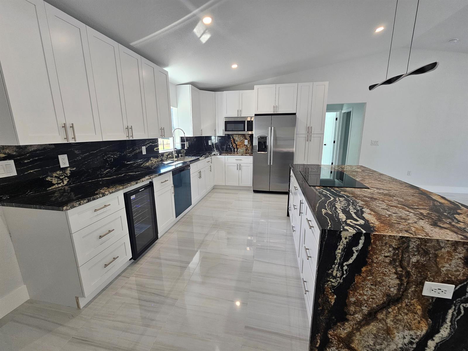 A modern kitchen features white cabinets, black granite countertops, stainless steel appliances, and tile flooring — 2964 NW 36th Avenue, Okeechobee FL 34972, OKEECHOBEE, FL