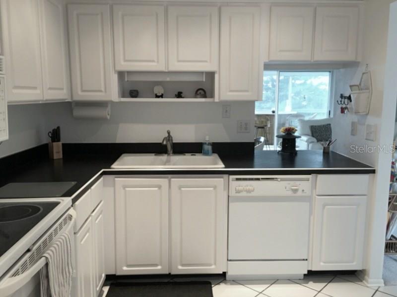 A kitchen features white cabinets, black countertops, a white sink, and a white dishwasher — 3660 IRONWOOD CIRCLE UNIT 503M, BRADENTON, FL