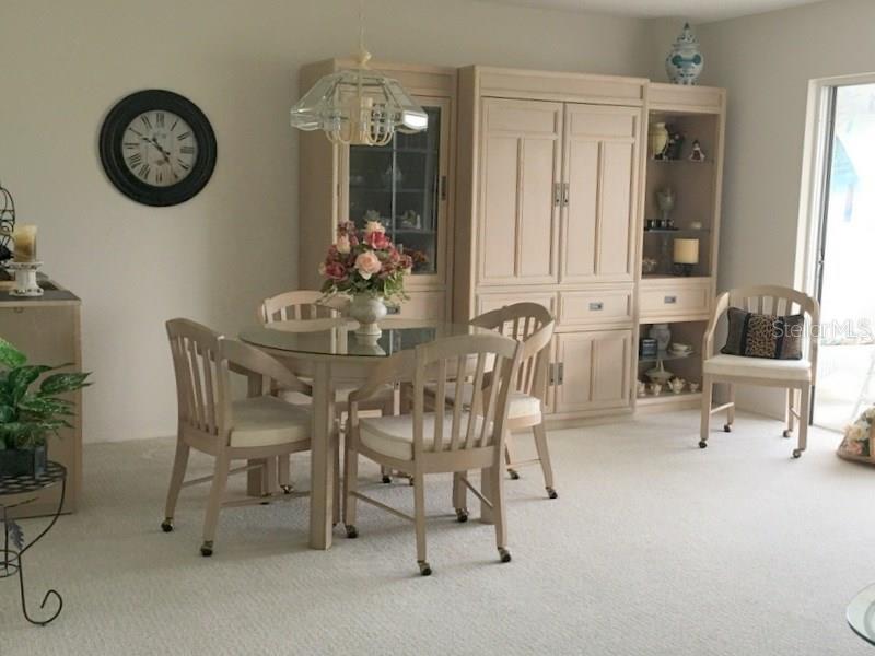 A dining room features a glass-topped table, light-colored wooden furniture, and a wall clock — 3660 IRONWOOD CIRCLE UNIT 503M, BRADENTON, FL