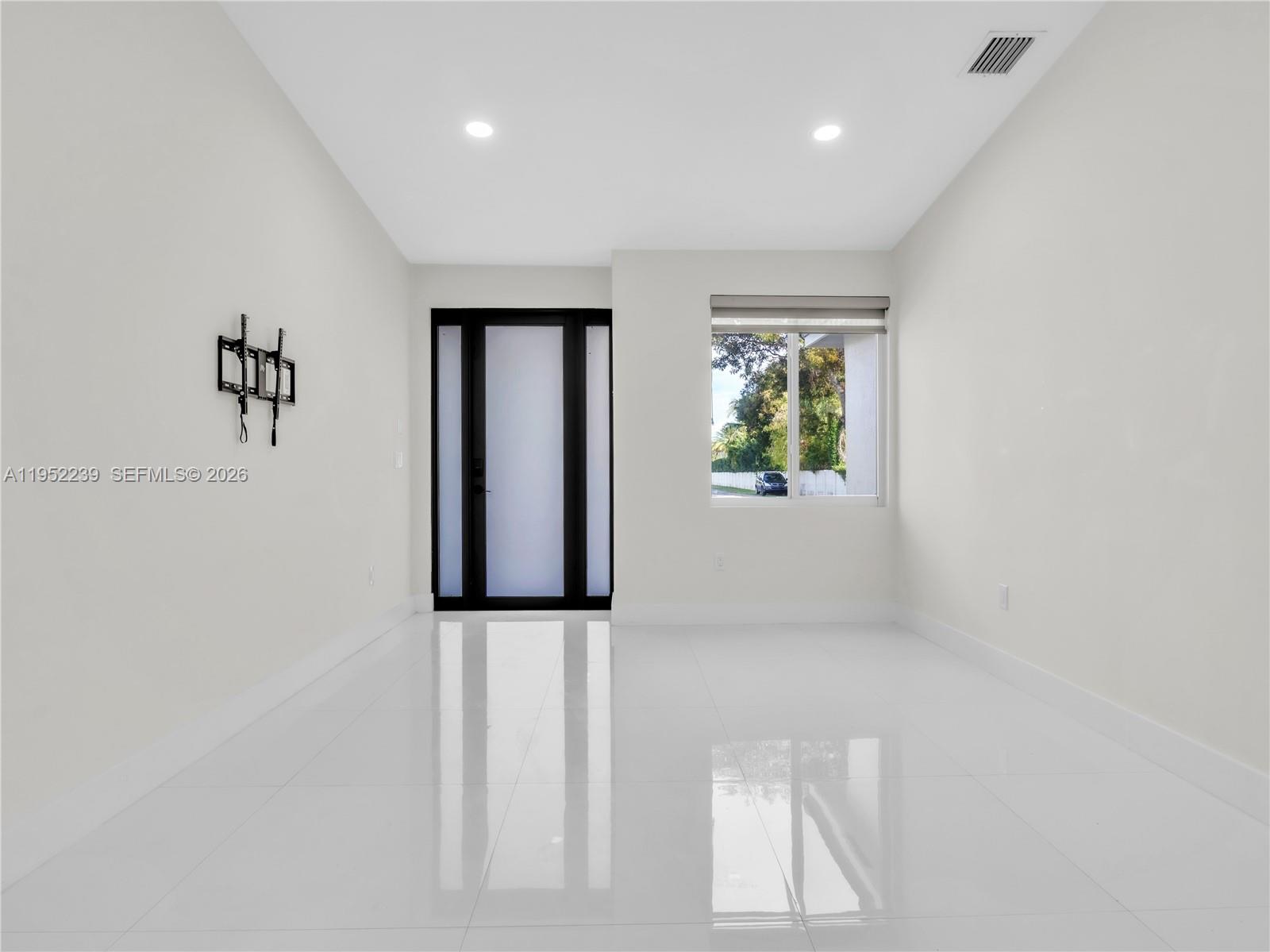 A minimalist room features white walls, glossy tile flooring, a black-framed door, and a window — 12608 SW 121st Ave, Miami FL 33186, MIAMI, FL