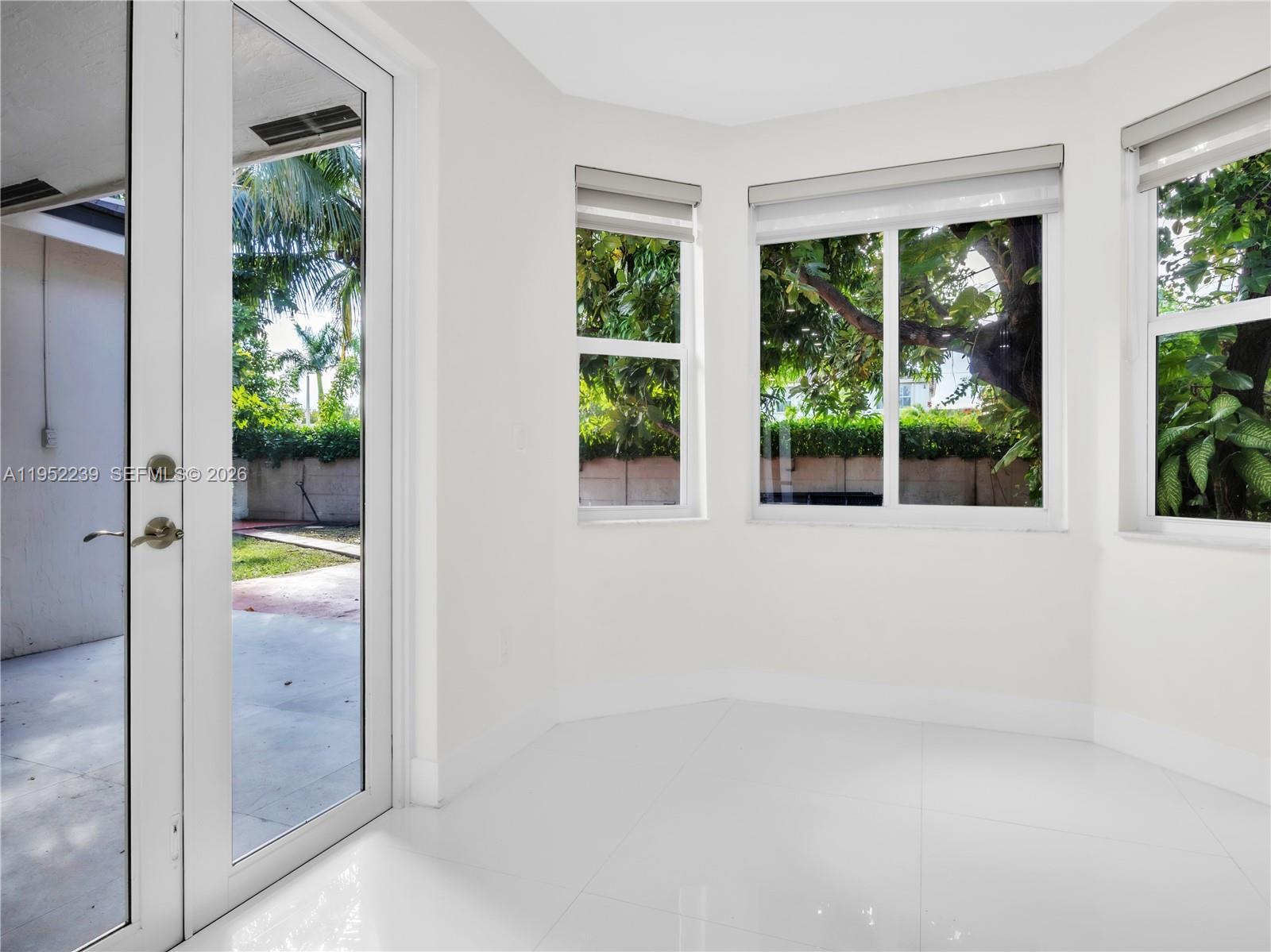 A bright room with white tile floors, large windows, and a glass door to outside — 12608 SW 121st Ave, Miami FL 33186, MIAMI, FL