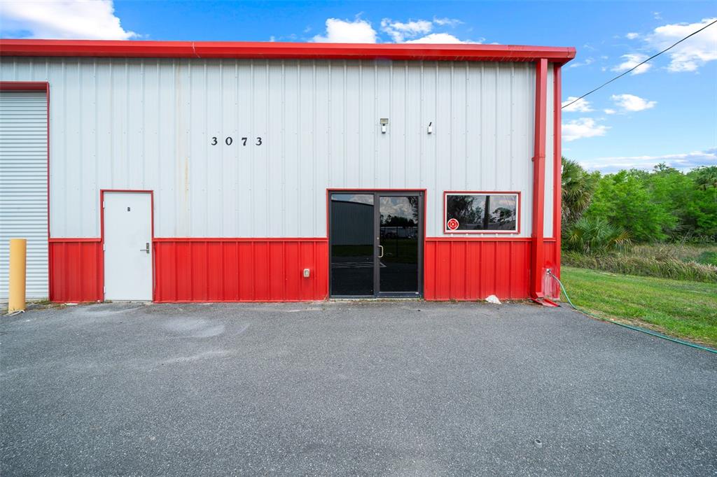 The exterior of a metal industrial building features red and white siding with two doors — 3073 NE 37TH PLACE, WILDWOOD, FL