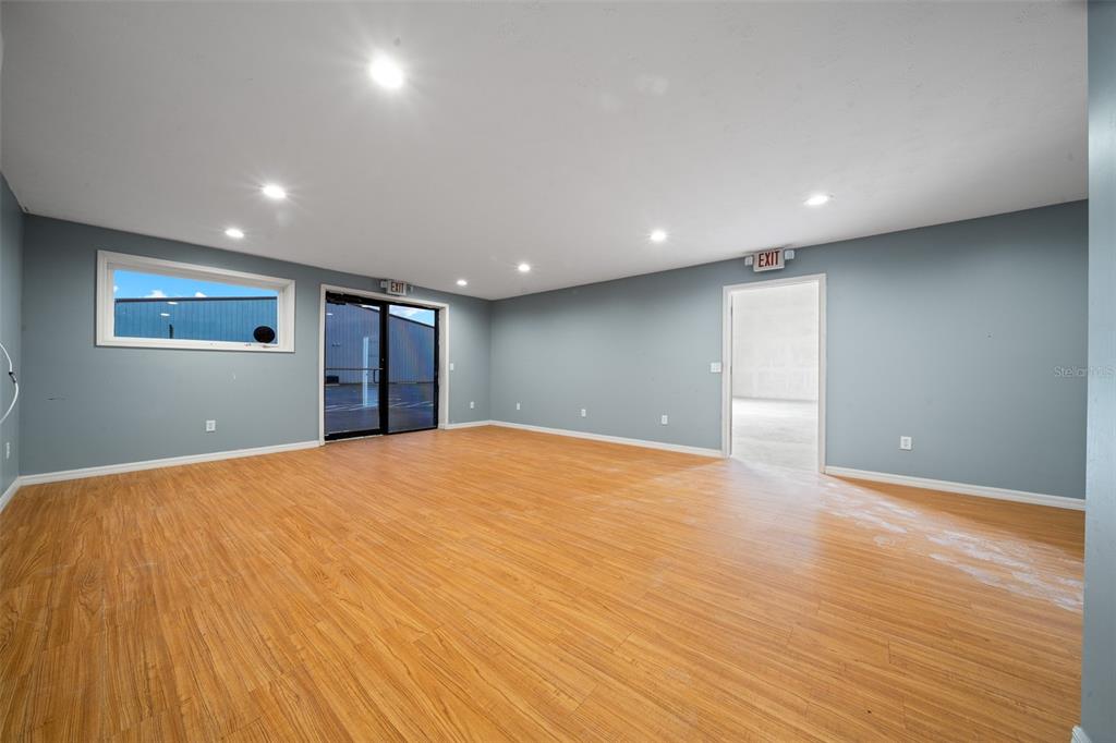 An empty room features light wood-look flooring, blue walls, recessed lighting, and two exit doors — 3073 NE 37TH PLACE, WILDWOOD, FL