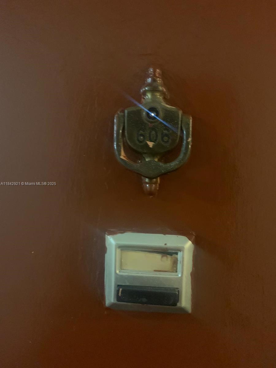 A brass door knocker with the number 606 is mounted above a doorbell on a door — 2025 NE 164th St # 606, North Miami Beach FL 33162, NORTH MIAMI BEACH, FL