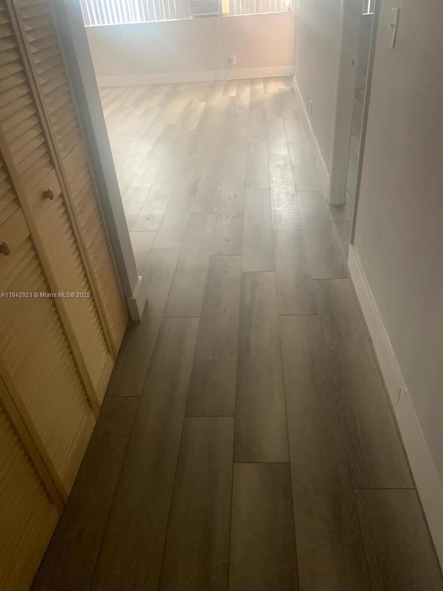 A hallway with light wood-look flooring leads into a room with a window — 2025 NE 164th St # 606, North Miami Beach FL 33162, NORTH MIAMI BEACH, FL