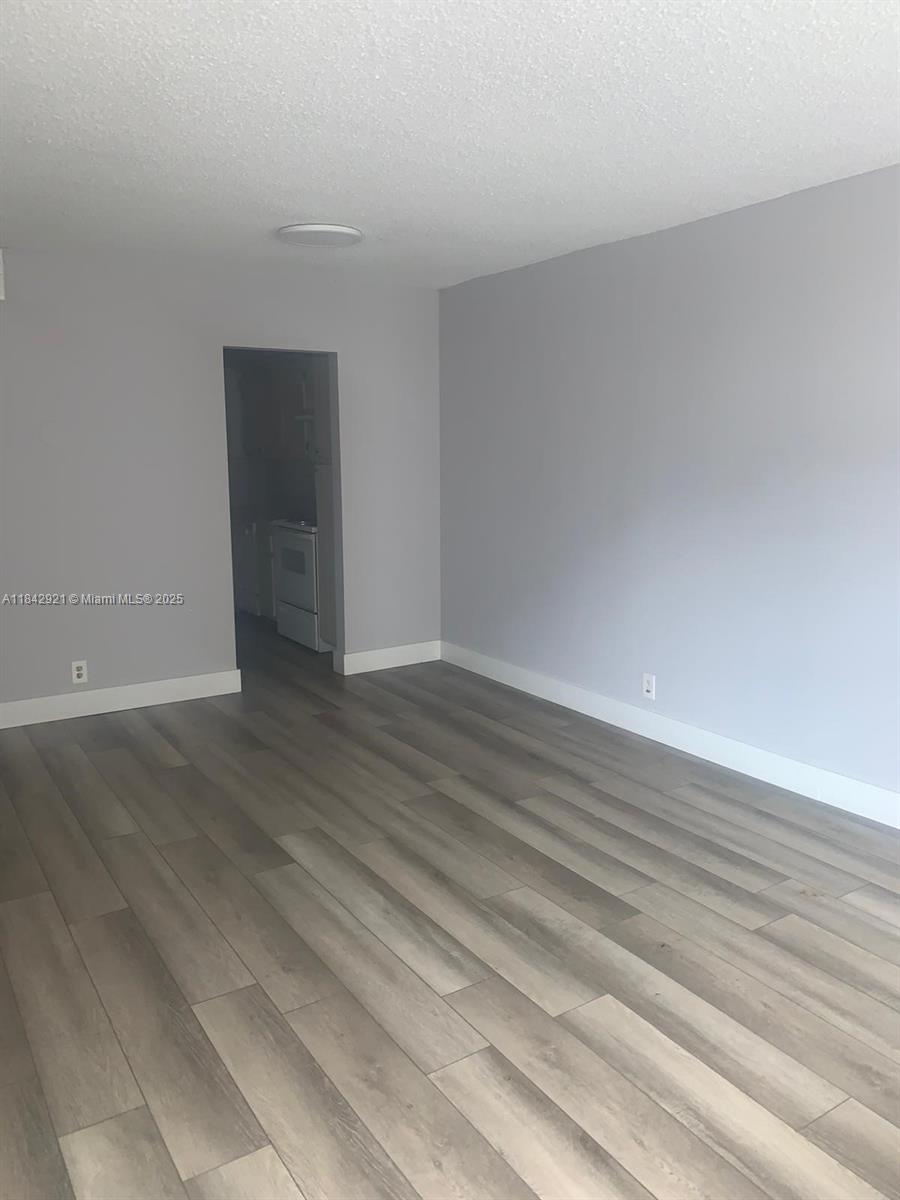 This room features gray walls, white baseboards, and light-colored wood-look flooring — 2025 NE 164th St # 606, North Miami Beach FL 33162, NORTH MIAMI BEACH, FL