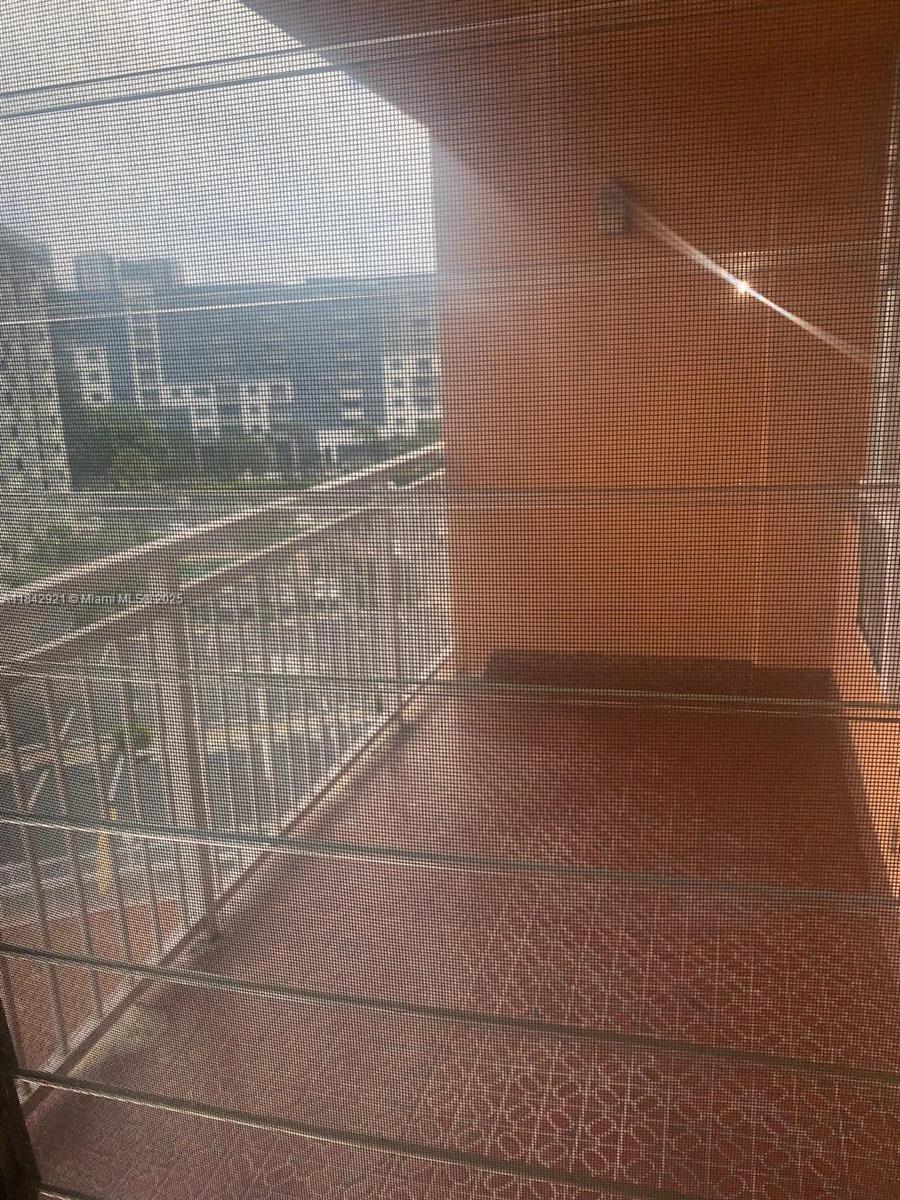 A balcony with a metal railing and a mesh screen overlooking a city street — 2025 NE 164th St # 606, North Miami Beach FL 33162, NORTH MIAMI BEACH, FL