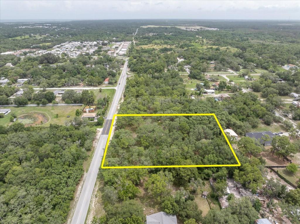 An aerial view shows a rectangular, tree-covered lot outlined in yellow next to a road — 0 HICKS ROAD, HUDSON, FL