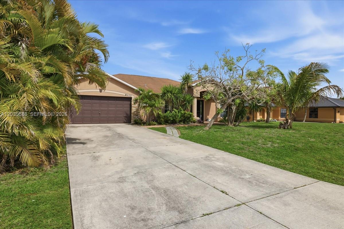 A single-story house with a concrete driveway, a two-car garage, and surrounding palm trees — 403 SW 28th PL, Cape Coral FL 33991, CAPE CORAL, FL