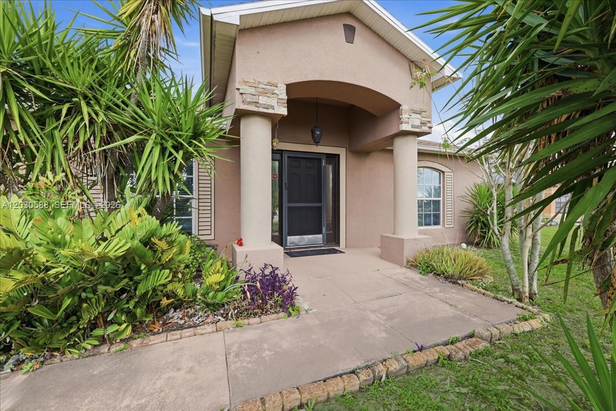 The exterior of a tan house features a covered entryway with stone-accented columns — 403 SW 28th PL, Cape Coral FL 33991, CAPE CORAL, FL