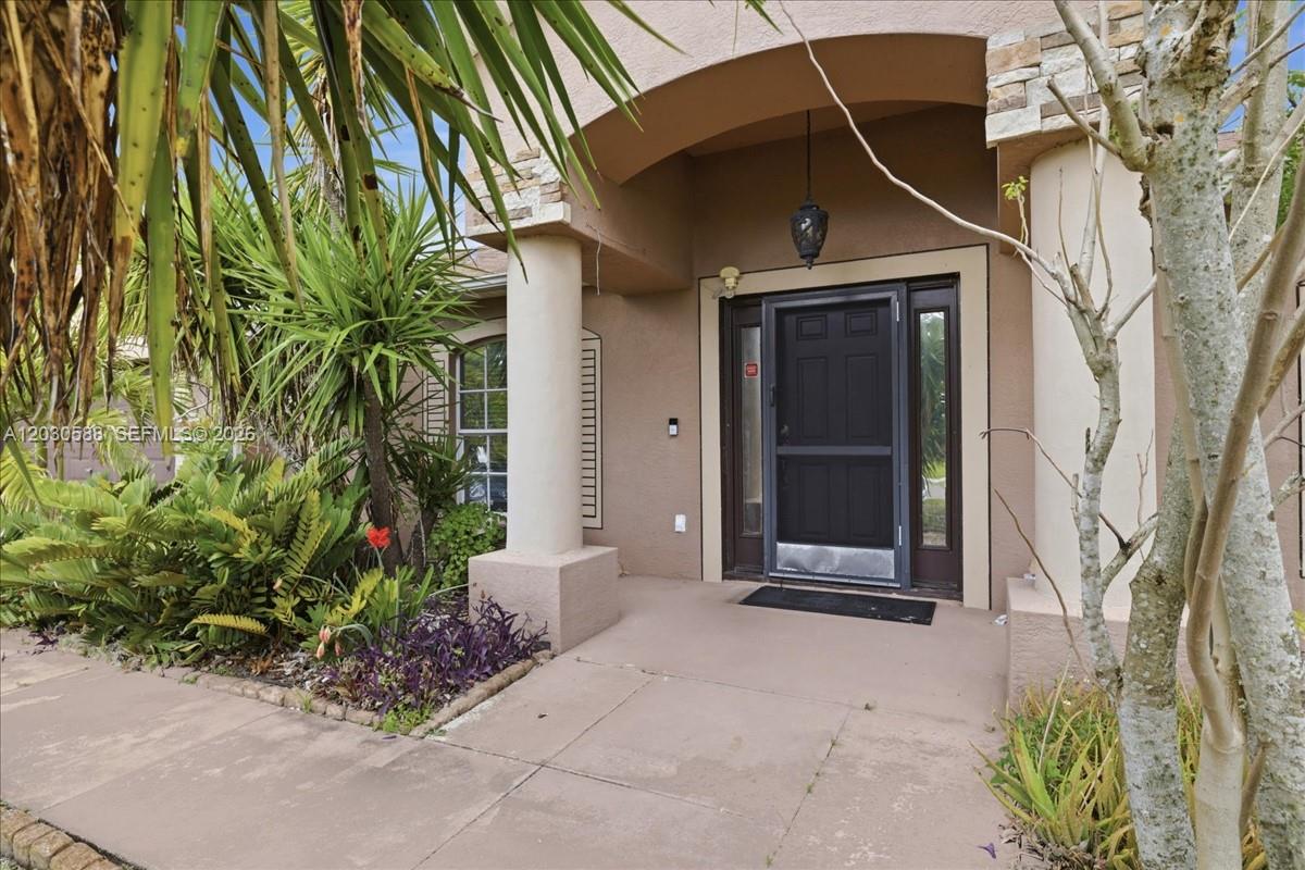 The front entrance of a house features a concrete porch, a column, and a screen door — 403 SW 28th PL, Cape Coral FL 33991, CAPE CORAL, FL