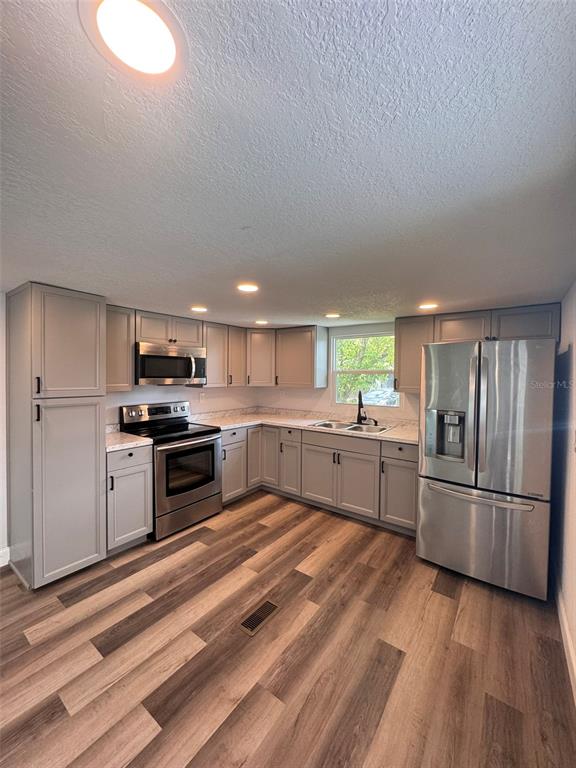 A kitchen features gray cabinets, stainless steel appliances, and wood-look flooring — 904 ROBINSON AVENUE, ST CLOUD, FL