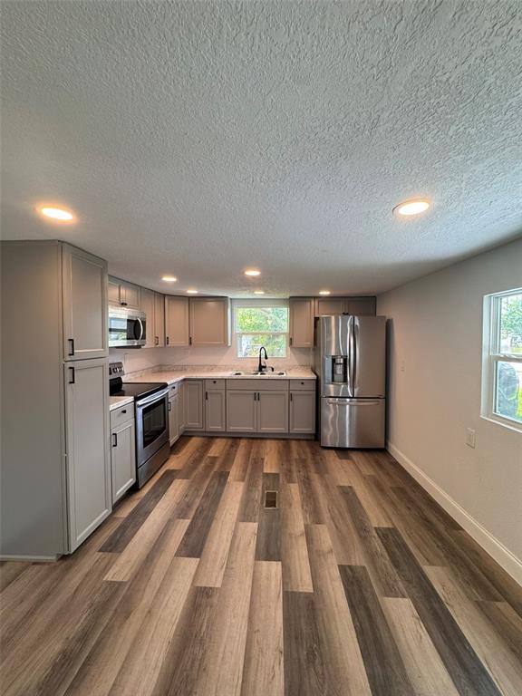 A kitchen with grey cabinets, stainless steel appliances, and wood-look flooring — 904 ROBINSON AVENUE, ST CLOUD, FL