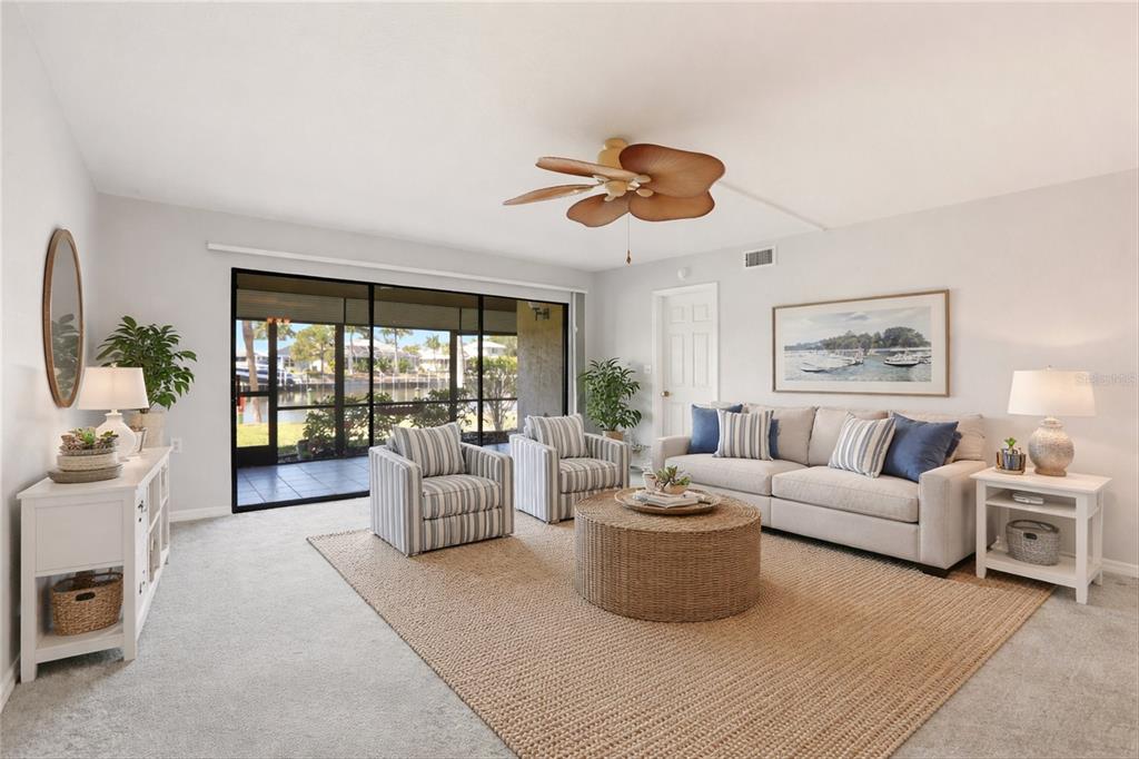A living room features a beige sofa, two striped armchairs, a round coffee table, and a ceiling fan — 601 SHREVE STREET UNIT 25A, PUNTA GORDA, FL