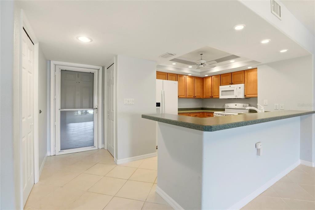 A kitchen with wood cabinets, a breakfast bar, and a tiled floor near an entryway — 601 SHREVE STREET UNIT 25A, PUNTA GORDA, FL